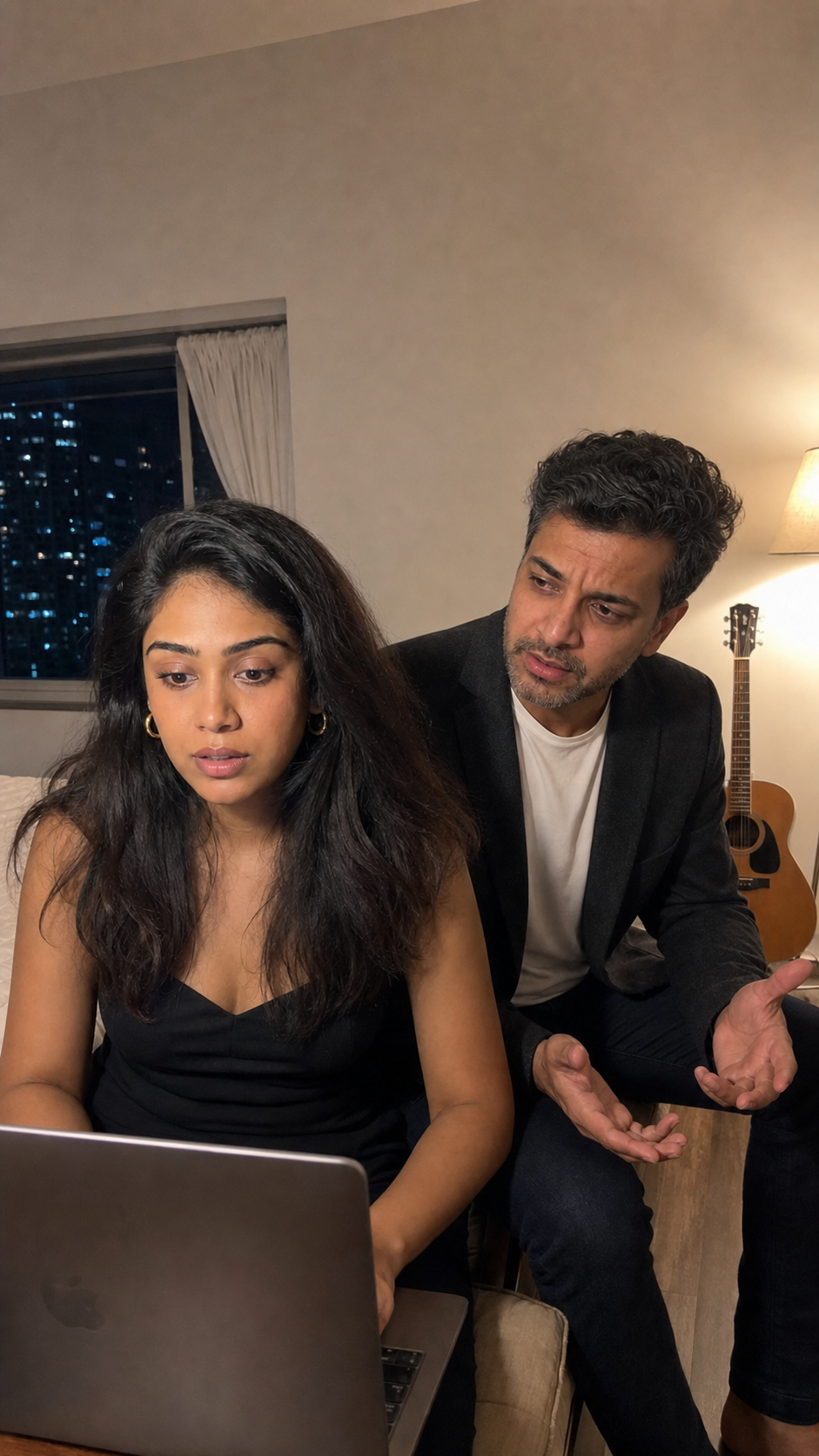 A woman focused on her laptop while her husband tries to talk to her